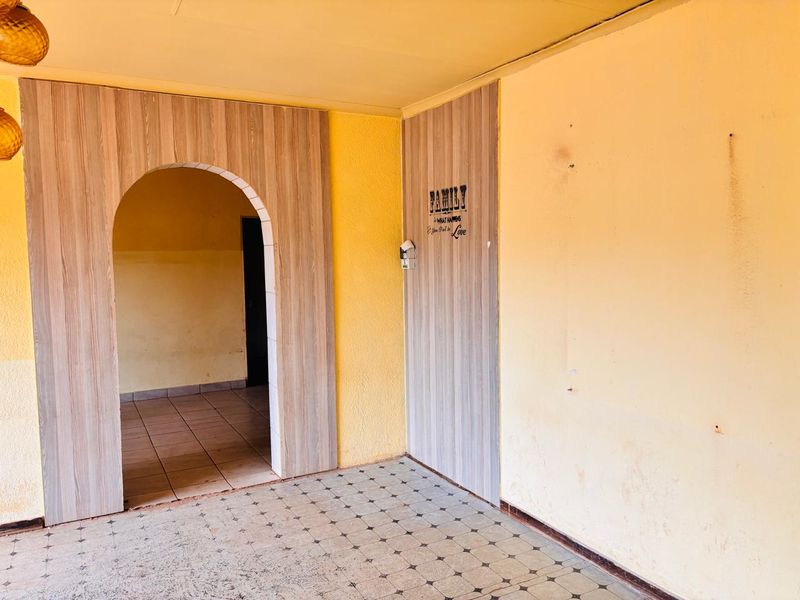 An interior living space featuring a decorative arched doorway with wood-look paneling and tiled flooring.
