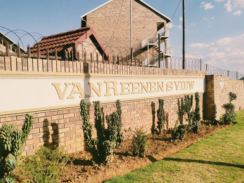 Exterior view of the Van Reenen's View apartment complex, featuring a brick boundary wall with security razor wire and landscaped garden beds.