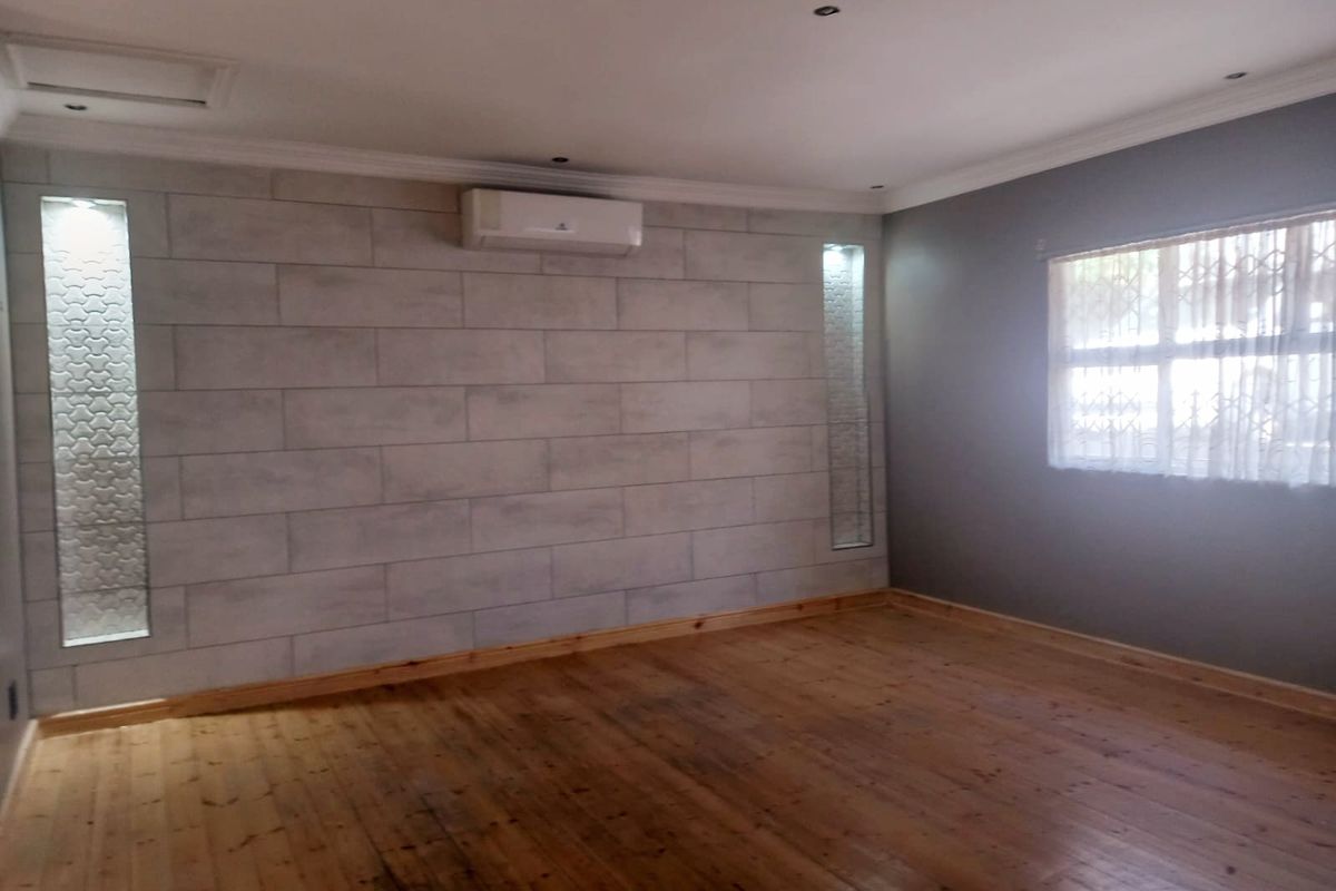Spacious living room featuring polished timber flooring, a feature wall with integrated lighting, and a wall-mounted air conditioning unit.
