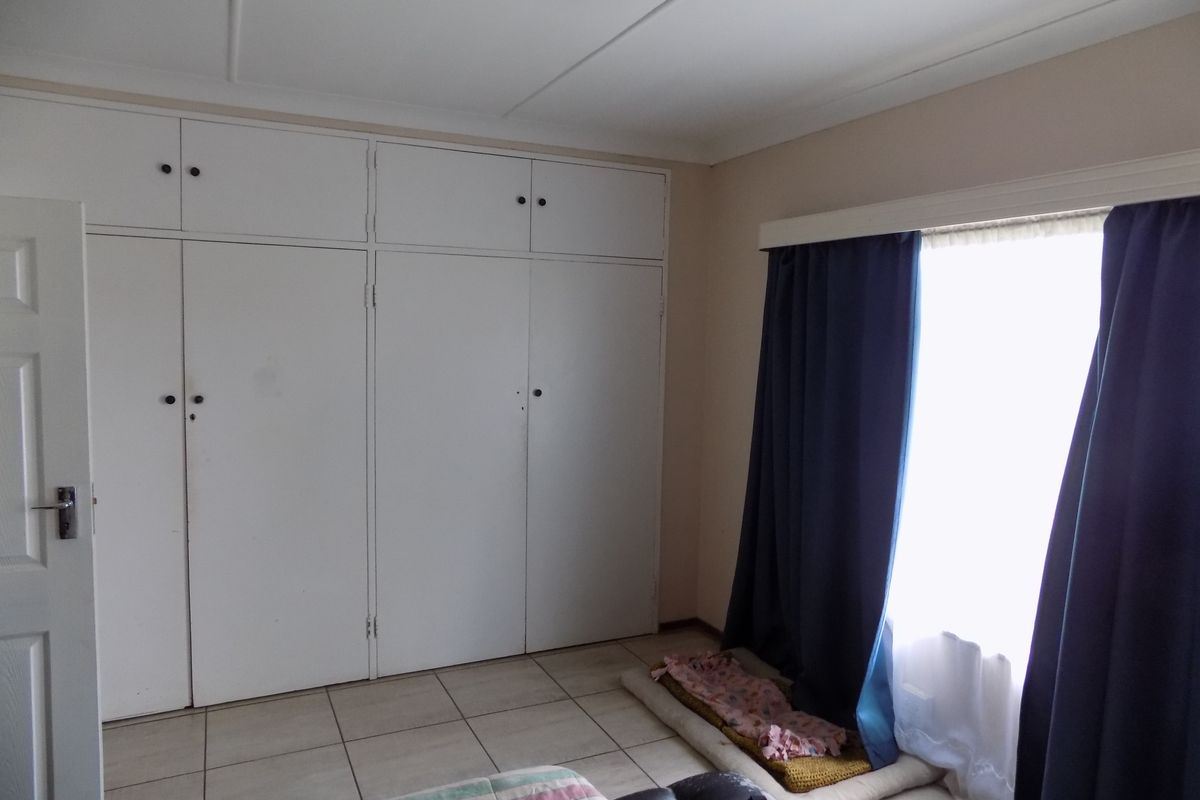 A bedroom featuring built-in cupboards and tiled flooring, providing a functional space with natural light from the window.