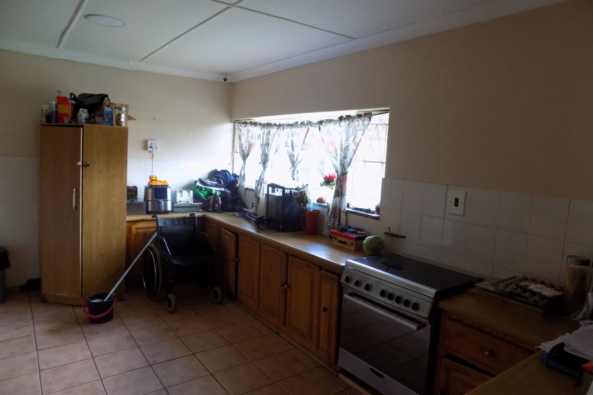 A functional kitchen featuring wooden cabinetry, tiled flooring, and a freestanding stove, offering potential for modernization and aesthetic updates.