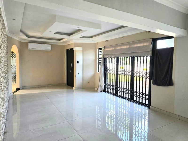 Spacious, empty living area featuring polished porcelain floor tiles, a modern recessed ceiling, and a stone feature wall with an installed air conditioning unit.