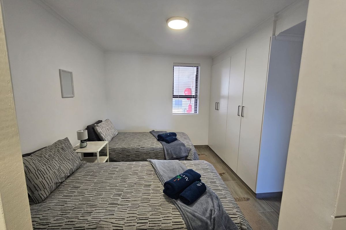 A well-maintained bedroom featuring built-in cupboards, tiled flooring, and a neutral color palette, offering a clean and functional living space.