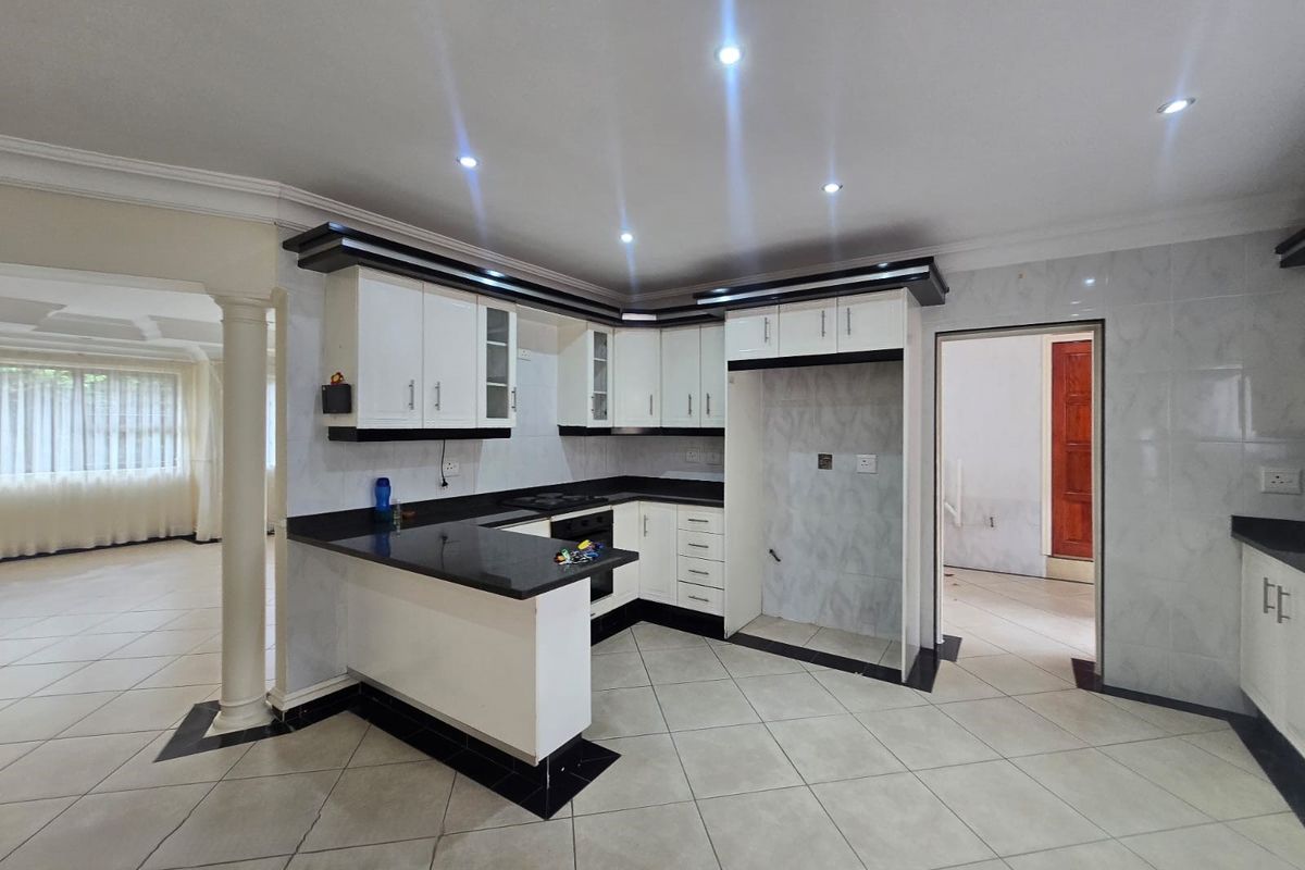 A modern, well-lit kitchen featuring white cabinetry, black granite countertops, a breakfast bar, and tiled flooring, offering a clean and functional workspace.