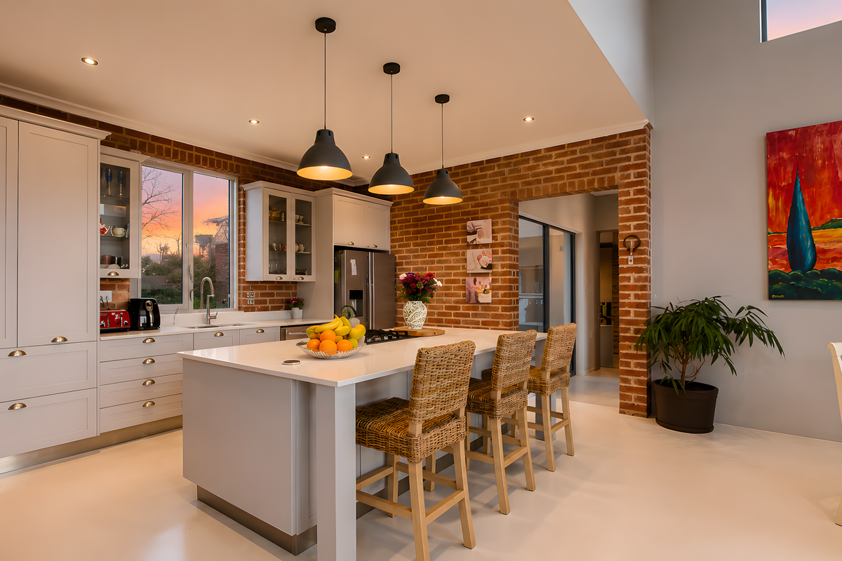 Modern kitchen featuring a central island with quartz countertops, shaker cabinetry, and exposed brick accents, complemented by stylish pendant lighting.
