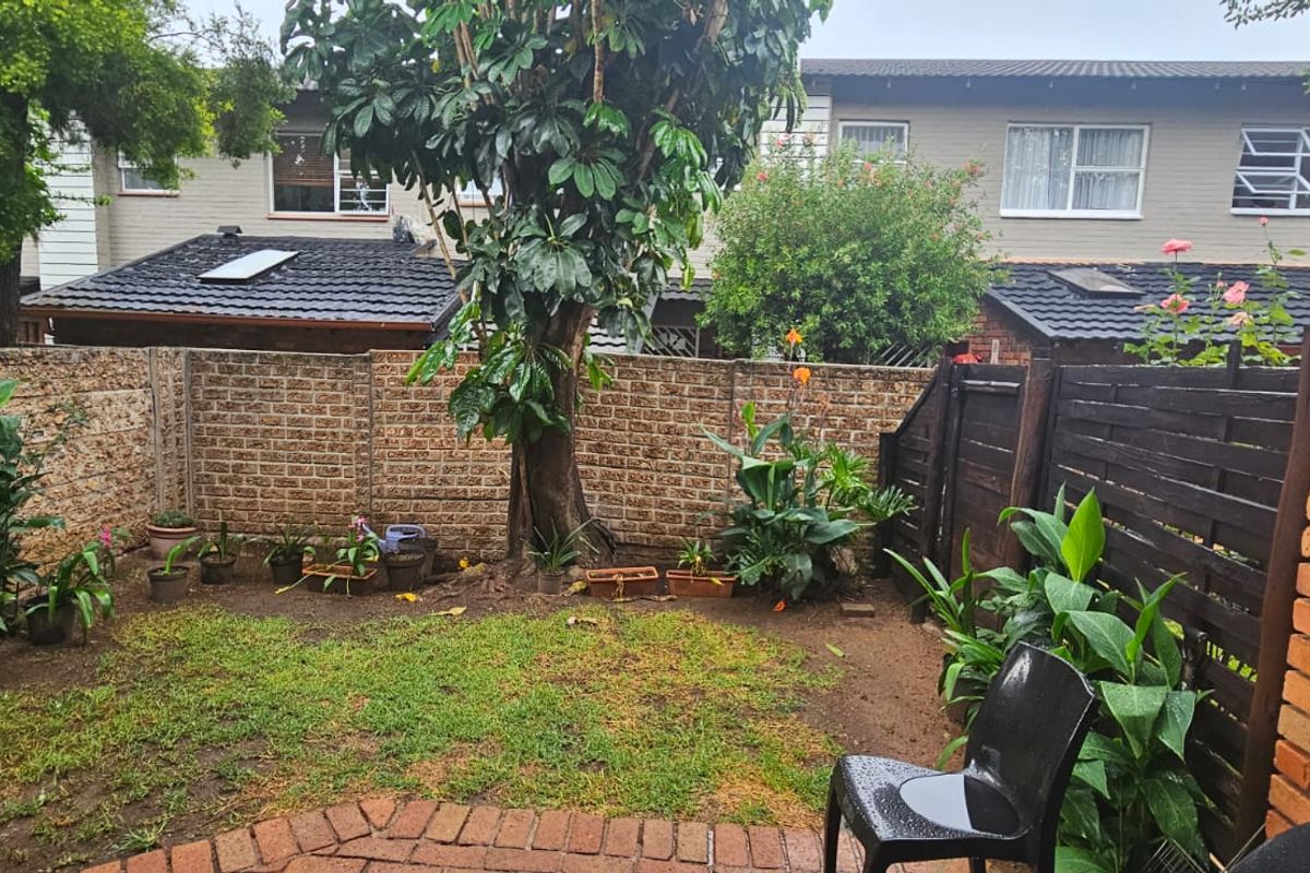A private rear garden featuring a small lawn, paved patio area, and established boundary walls with timber fencing.