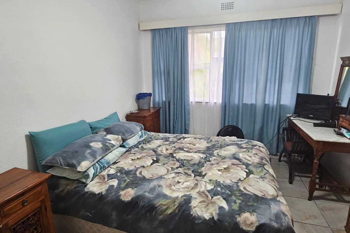 A functional bedroom featuring tiled flooring and a window with a fitted curtain rail, providing a neutral base for potential interior updates.