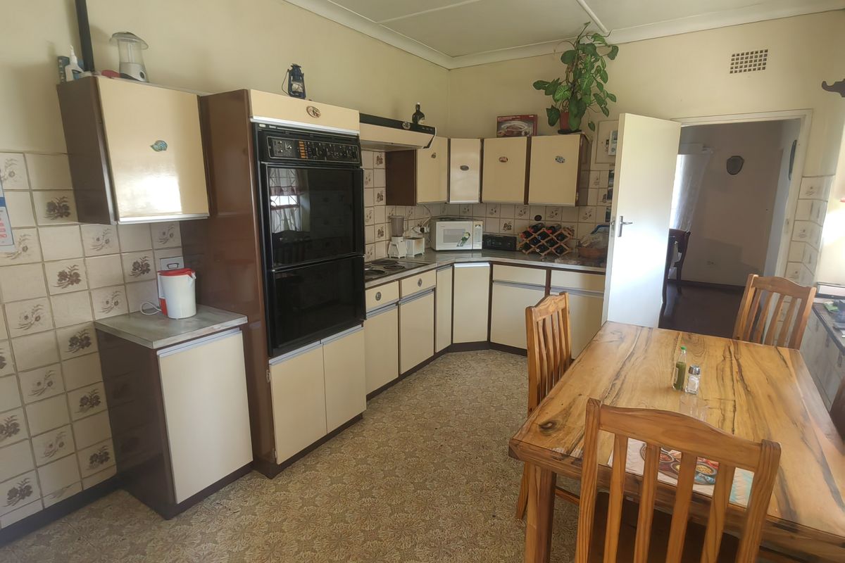 A dated kitchen featuring original cabinetry, integrated oven, hob, and tiled backsplash, offering significant potential for modernization and renovation.