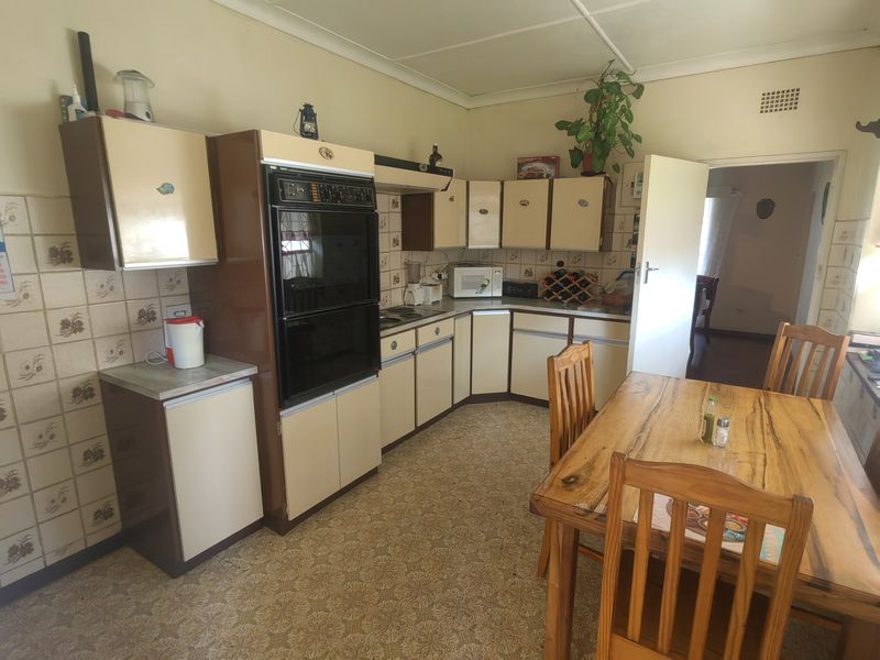 A dated kitchen featuring original cabinetry, integrated oven, hob, and tiled backsplash, offering significant potential for modernization and renovation.