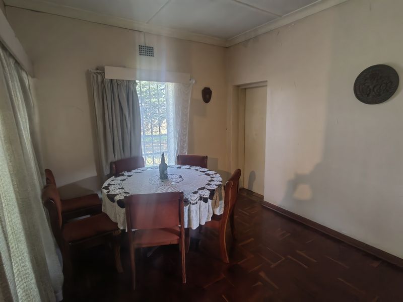 Dining room featuring traditional parquet flooring, neutral wall finishes, and a window fitted with security bars.