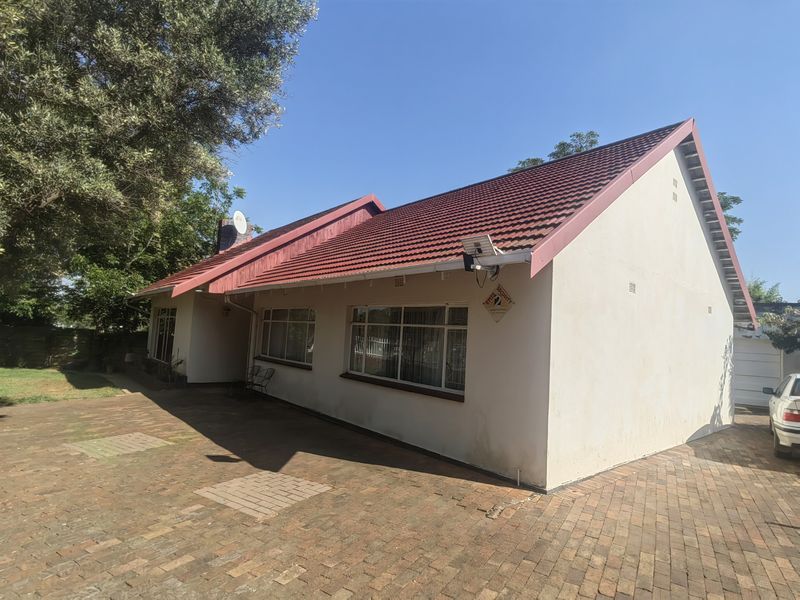 A view of the front exterior of the house featuring a tiled roof, paved driveway, and secure perimeter access.