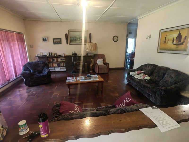Spacious living room featuring traditional parquet flooring and a brick fireplace, offering a classic layout with potential for modern updates.