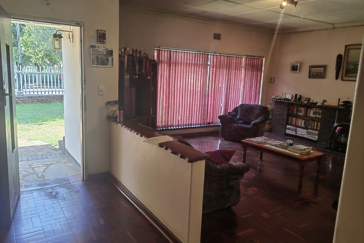Spacious living room featuring traditional parquet flooring, a brick fireplace, and direct access to the outdoor patio area.