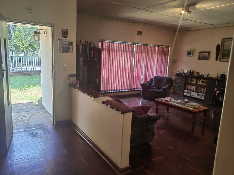 Spacious living room featuring traditional parquet flooring, a brick fireplace, and direct access to the outdoor patio area.