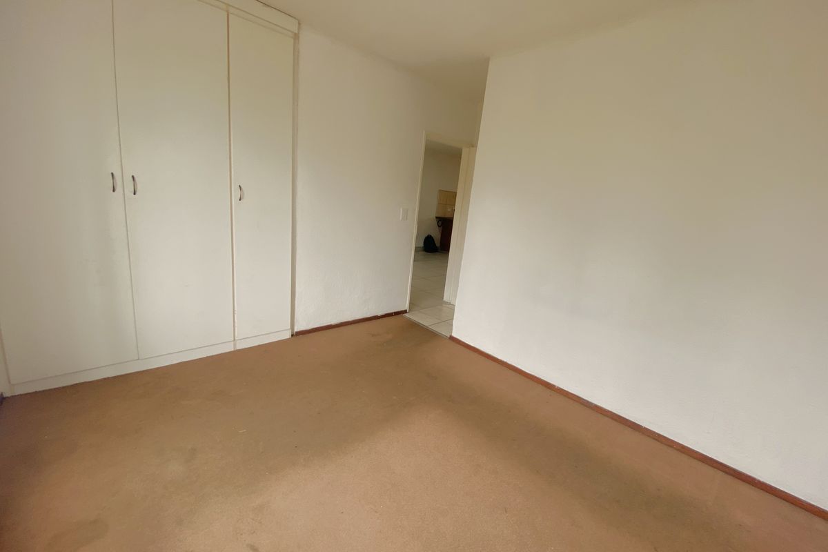 A vacant bedroom featuring built-in cupboards and carpeted flooring, offering a blank canvas for potential updates and personalization.
