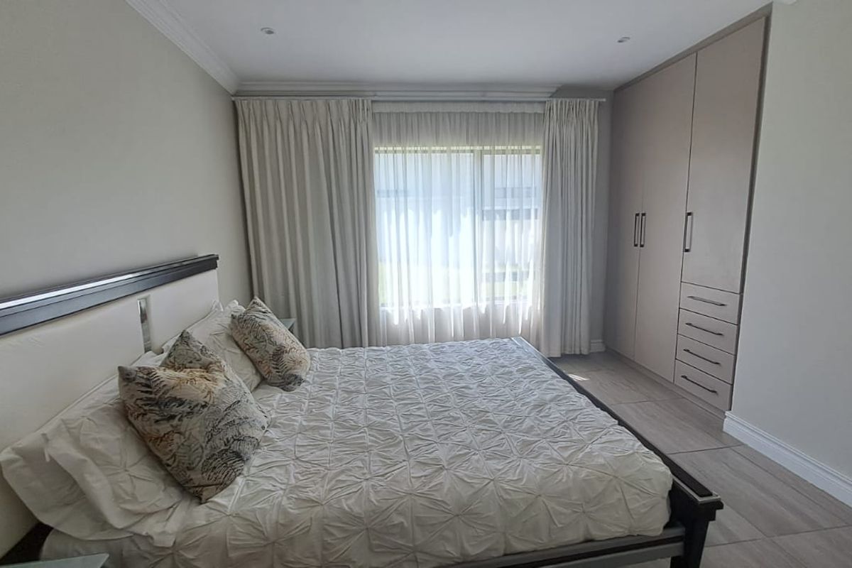A well-maintained bedroom featuring neutral tones, tiled flooring, recessed ceiling lighting, and ample built-in cupboard storage.