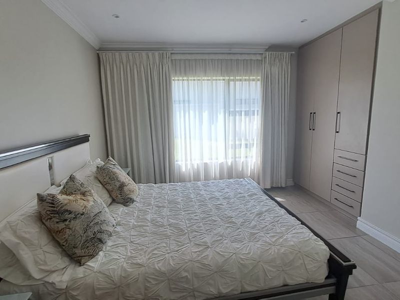 A well-maintained bedroom featuring neutral tones, tiled flooring, recessed ceiling lighting, and ample built-in cupboard storage.