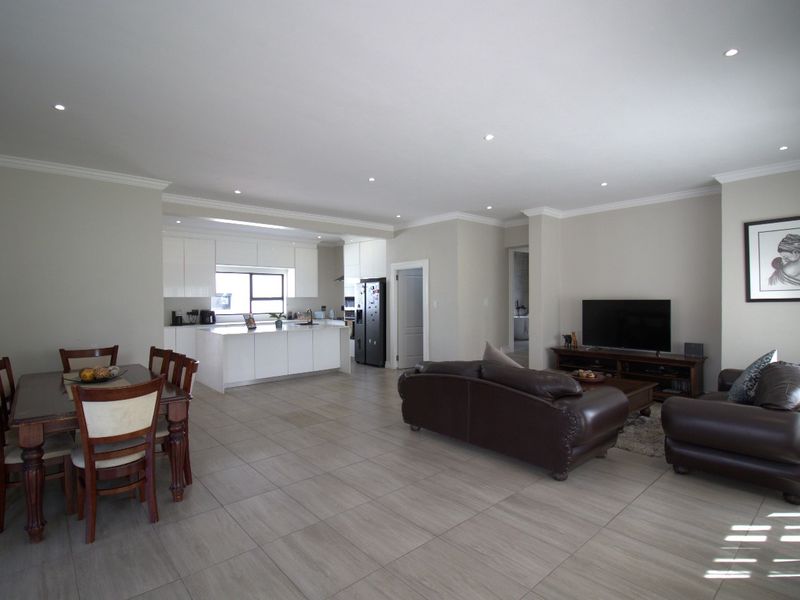 Spacious open-plan living area featuring a modern kitchen with island, tiled flooring, recessed lighting, and crown molding throughout the combined dining and lounge space.