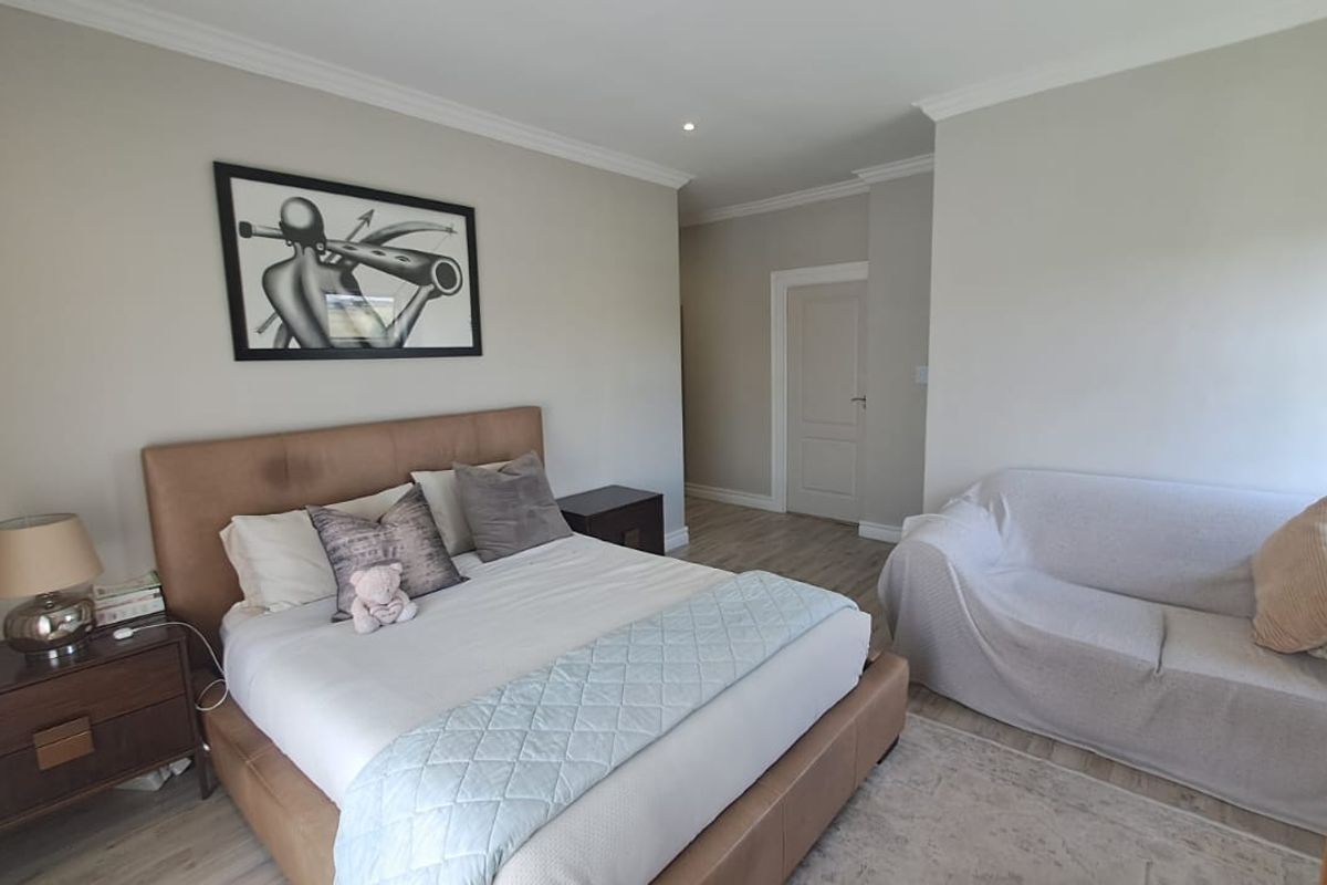 A well-maintained bedroom featuring neutral wall tones, crown molding, recessed lighting, and durable laminate flooring, offering a comfortable and clean living space.