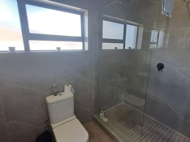 Modern bathroom featuring a walk-in shower with glass screen, tiled walls, and a contemporary toilet.