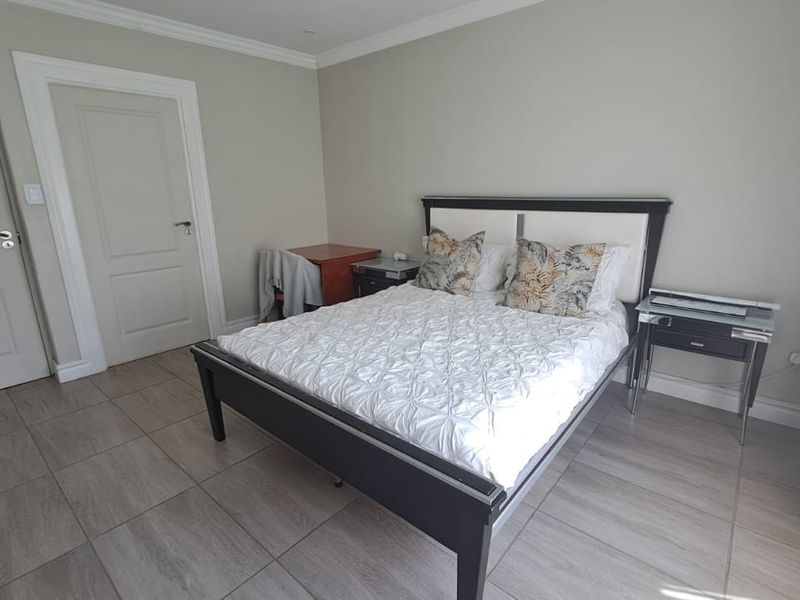 A well-maintained bedroom featuring neutral wall tones, tiled flooring, and classic architectural detailing including coved ceilings and panelled internal doors.