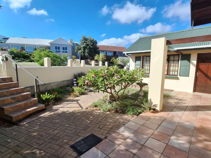 A well-maintained outdoor patio area featuring brick paving, tiled flooring, a timber pergola, and a staircase leading to the garden.