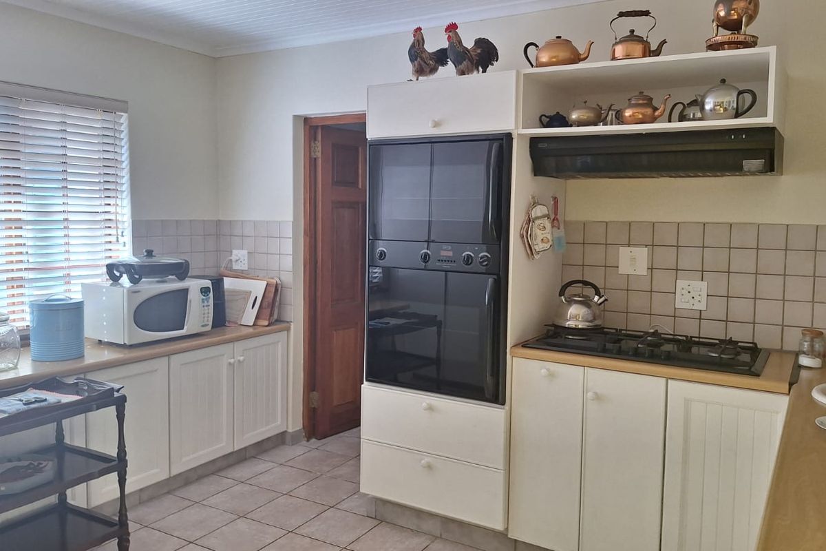 A functional kitchen featuring built-in cabinetry, a gas hob with extractor fan, a wall-mounted oven, and tiled finishes throughout.