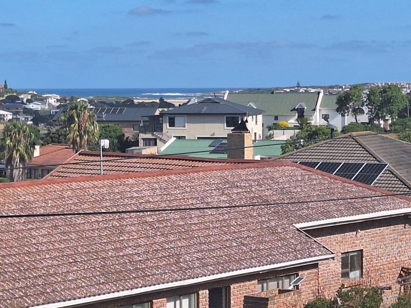 Elevated view overlooking the surrounding residential neighbourhood with distant ocean views and visible roof-mounted solar panels.