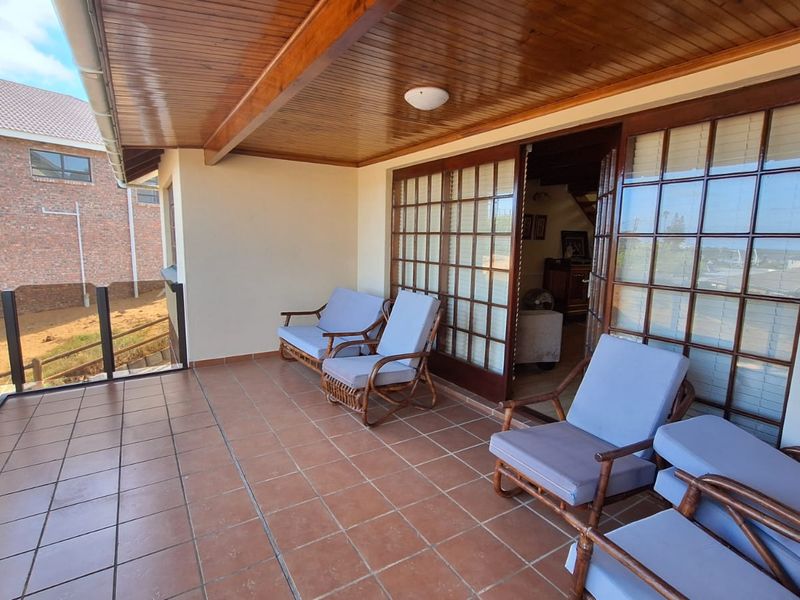 A covered patio featuring tiled flooring, a timber ceiling, and glass sliding doors, providing a seamless transition to the interior living space.