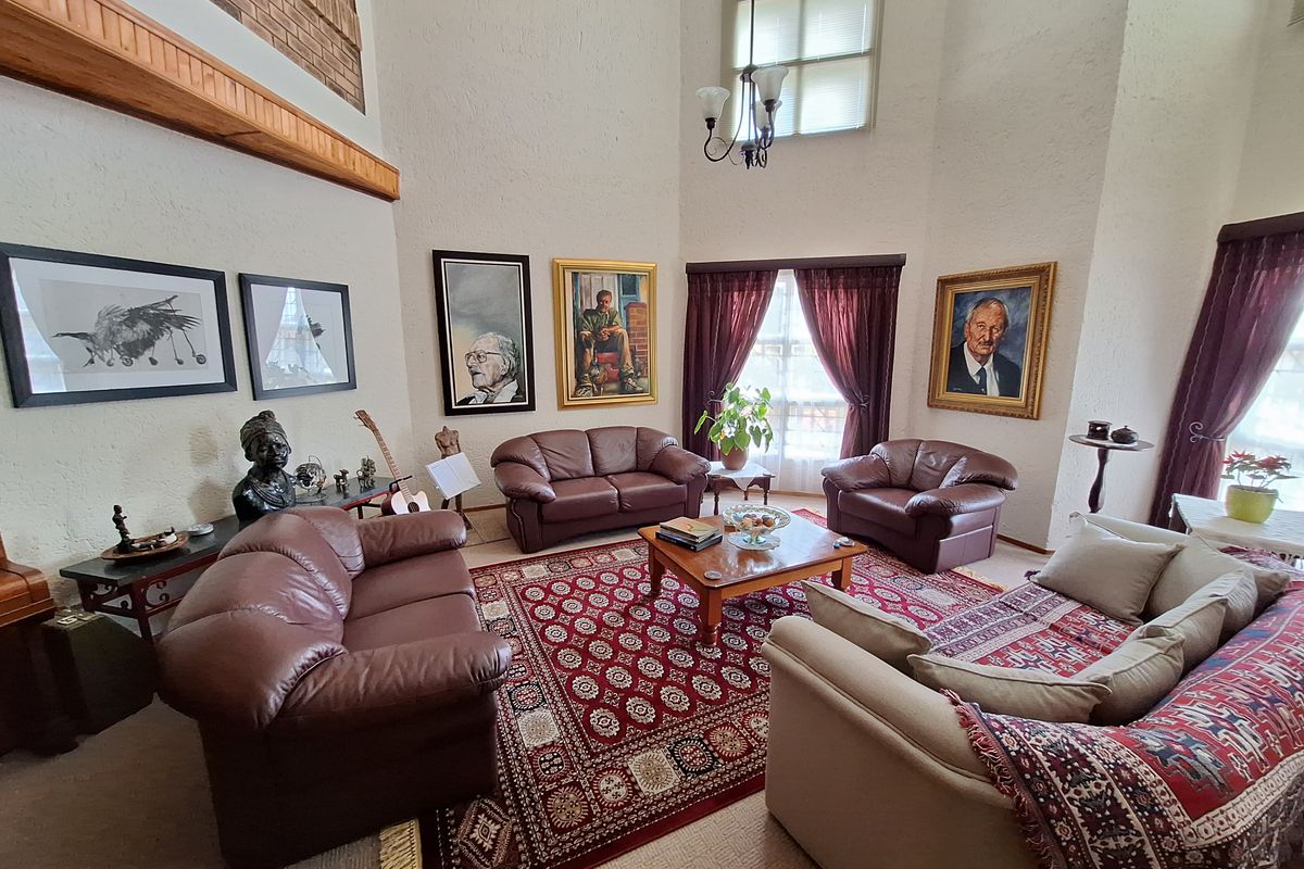 Spacious double-volume living room featuring high ceilings, large windows, and textured wall finishes, creating an airy and traditional atmosphere.