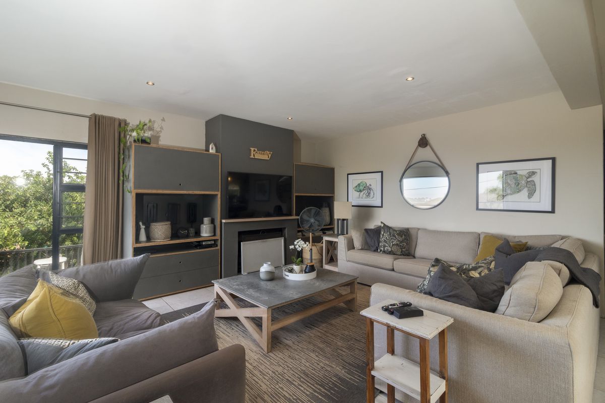 A comfortable living room featuring a built-in fireplace, recessed downlighting, and large windows providing natural light.