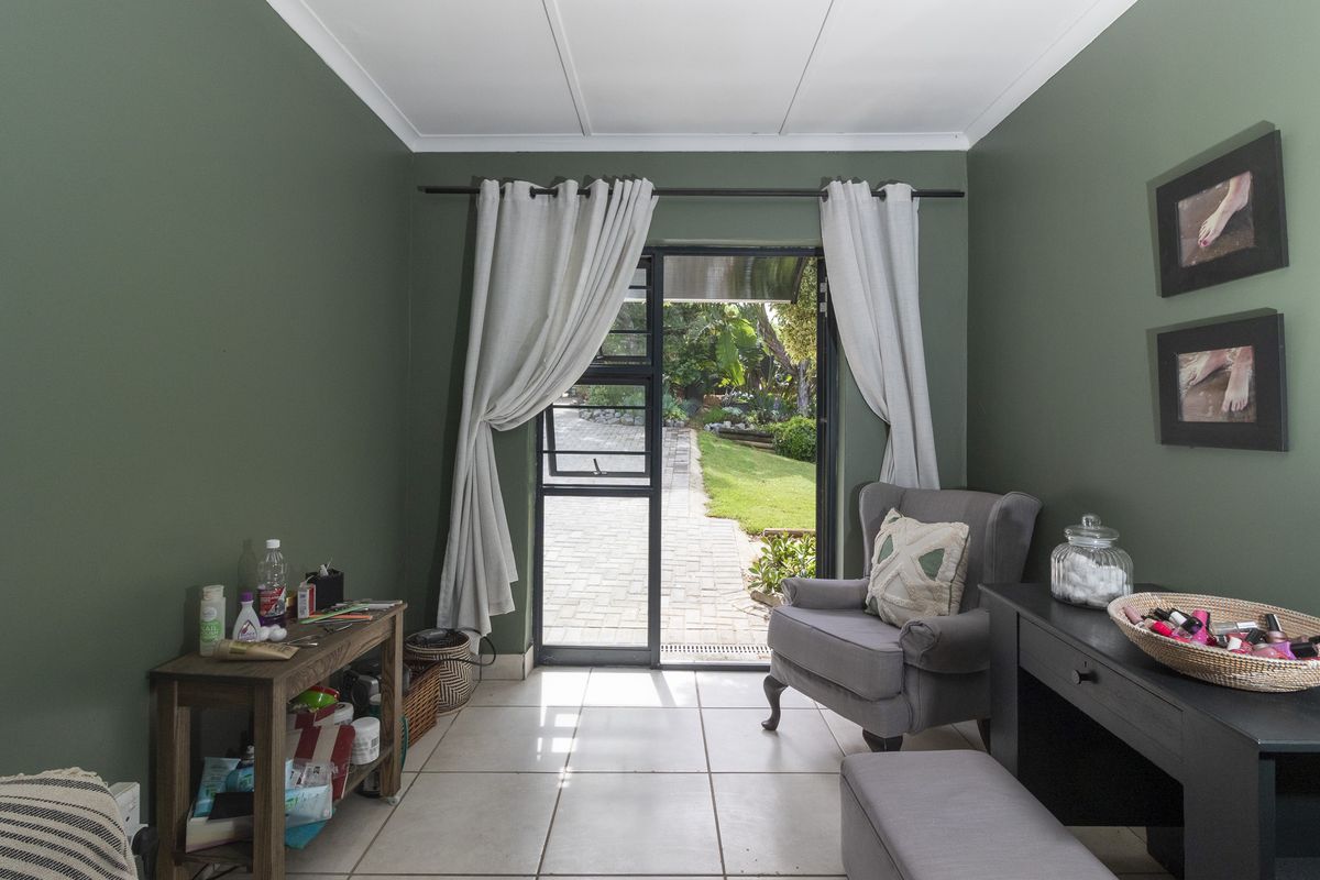 A bedroom featuring tiled flooring and direct access to the garden through an aluminium framed door.