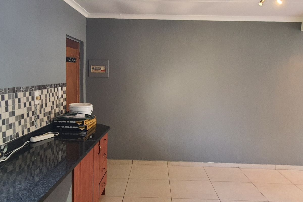 A functional kitchen area featuring dark granite countertops, a mosaic tile backsplash, and neutral ceramic floor tiles, offering a clean and practical workspace.