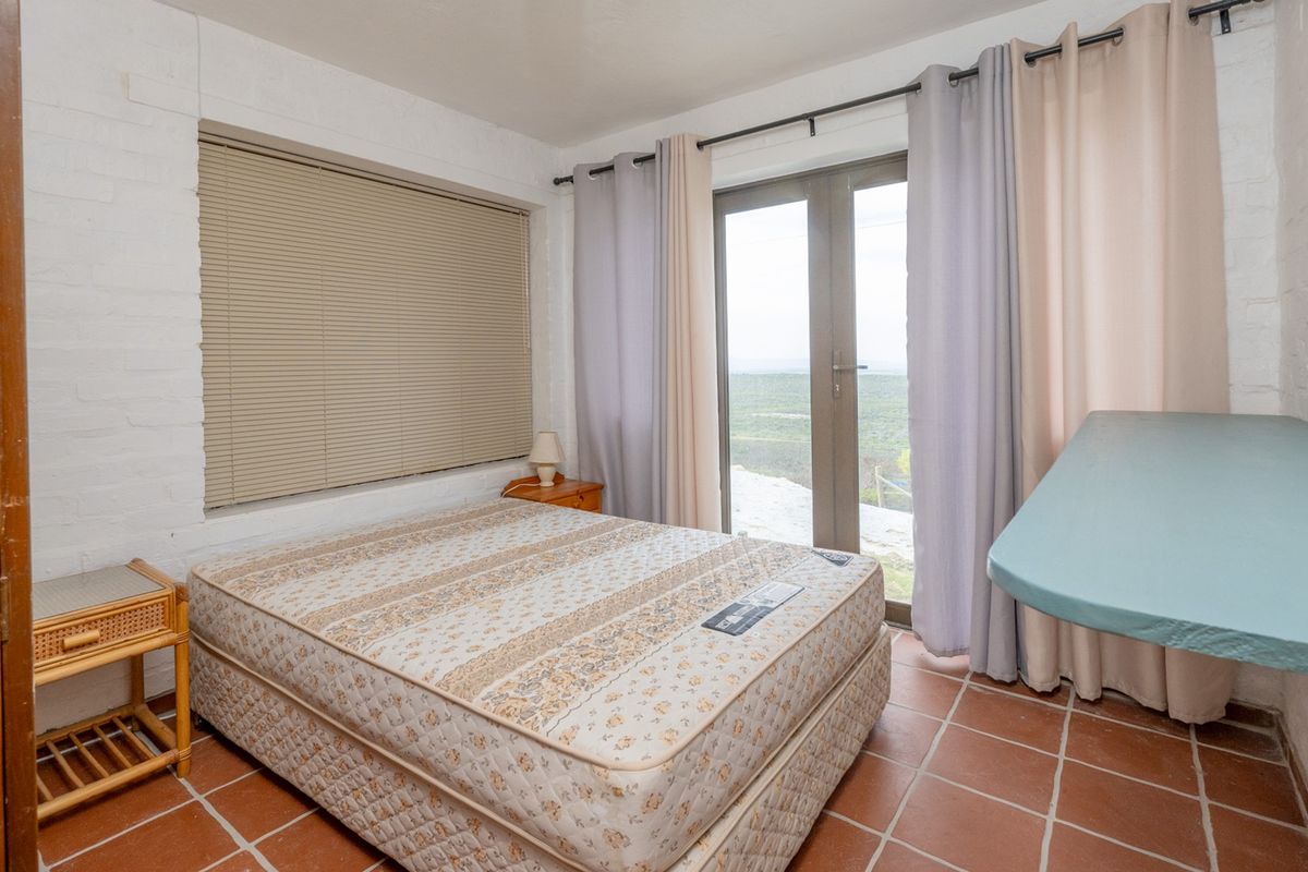 A bedroom featuring terracotta floor tiles, painted brick walls, and a glass sliding door providing access to the outdoors.