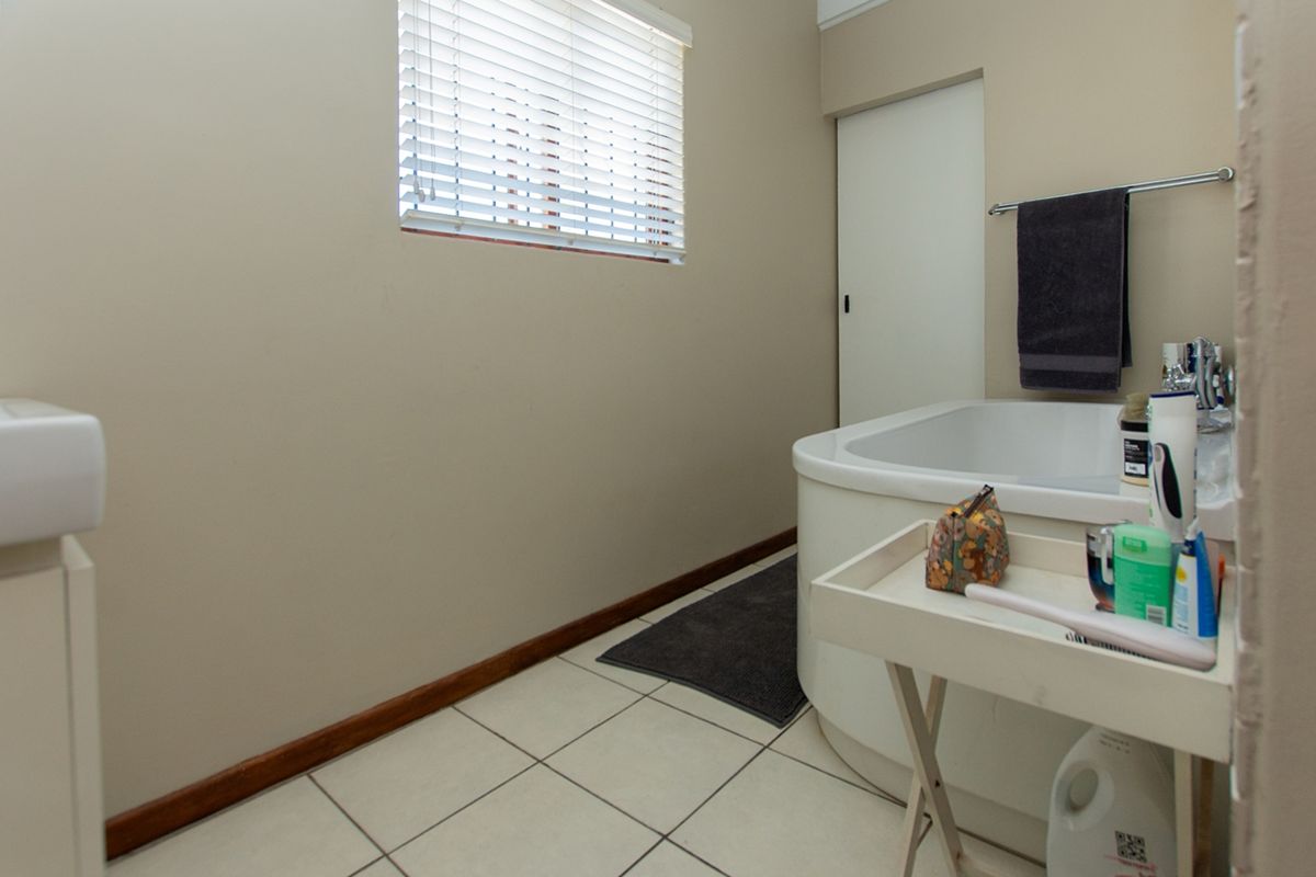 A functional bathroom featuring a built-in bathtub, tiled flooring, and a vanity basin, providing a clean and practical space.