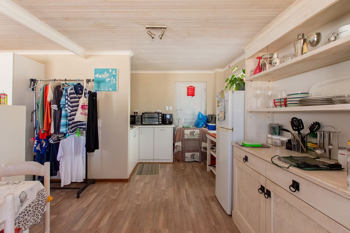 A functional kitchen area featuring built-in cabinetry, open shelving, and timber-clad ceilings, offering a practical layout with potential for modern updates.