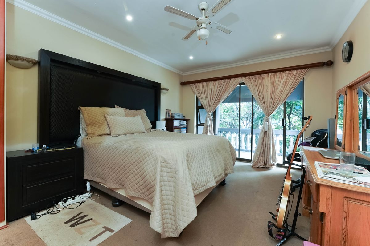 Spacious bedroom featuring a ceiling fan, built-in headboard, and sliding glass doors providing access to an outdoor balcony area.