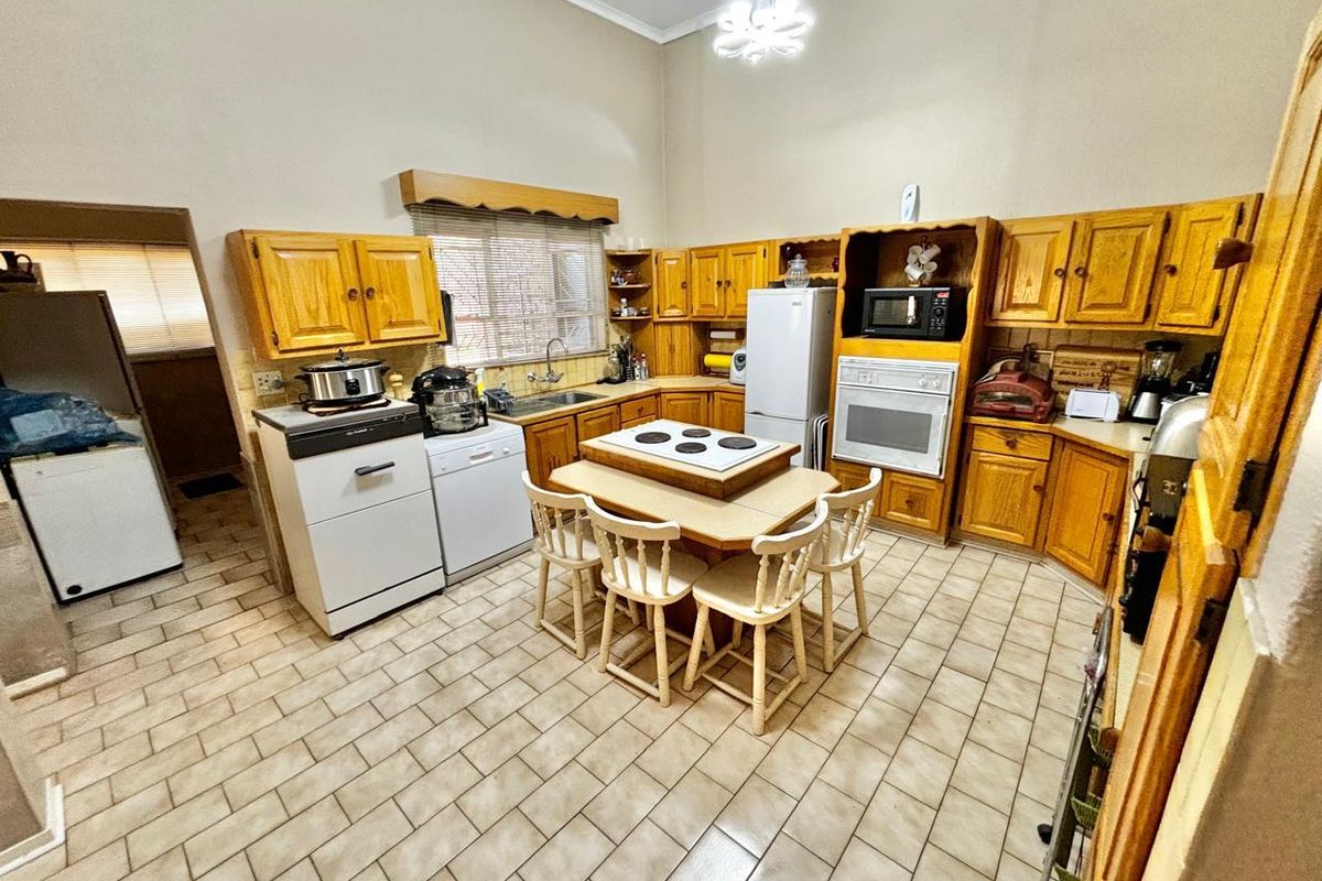 Spacious kitchen featuring traditional timber cabinetry, a central island with a built-in hob, and tiled flooring throughout.