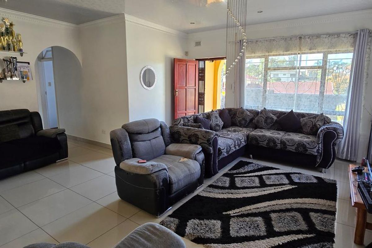 Spacious living room featuring large windows, tiled flooring, and an arched entryway leading to other areas of the home.