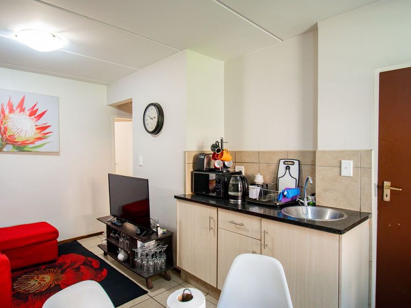 Compact open-plan living area featuring a kitchenette with granite countertops, stainless steel sink, and neutral cabinetry, seamlessly integrated with the living space.