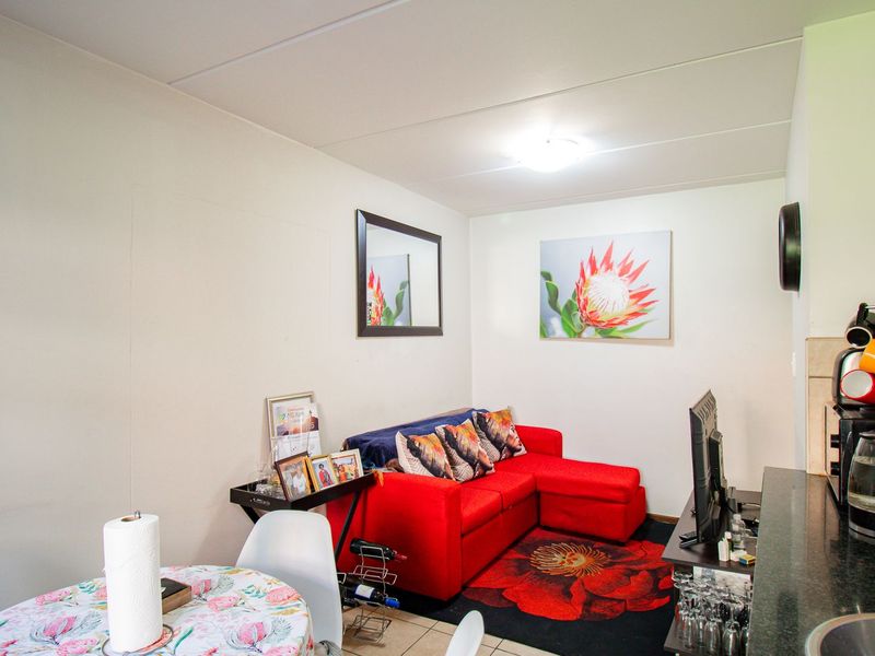 Compact open-plan living area featuring a functional kitchen space with granite countertops and tiled flooring, suitable for modern apartment living.