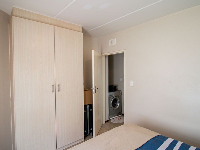Bedroom featuring a light wood-finish built-in wardrobe and direct access to a small utility area with laundry facilities.