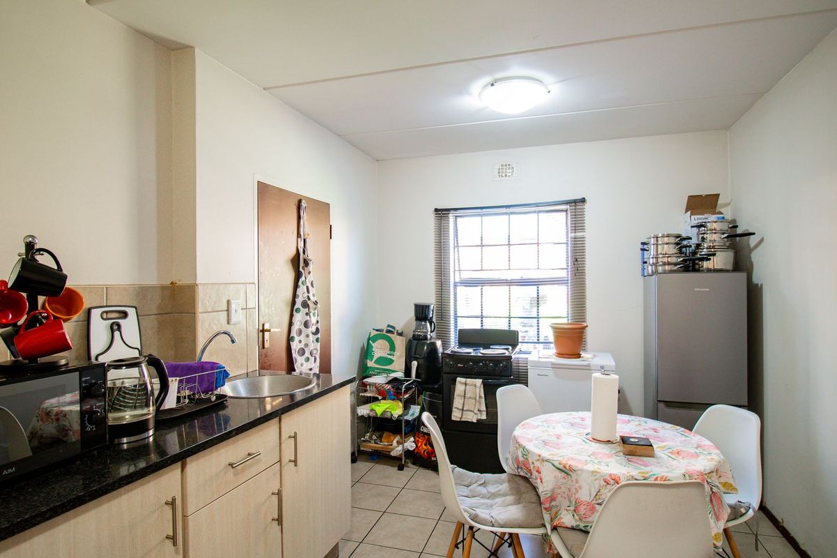 A functional kitchen featuring light-toned cabinetry, granite countertops, a stainless steel sink, and tiled flooring, providing a practical space for meal preparation.