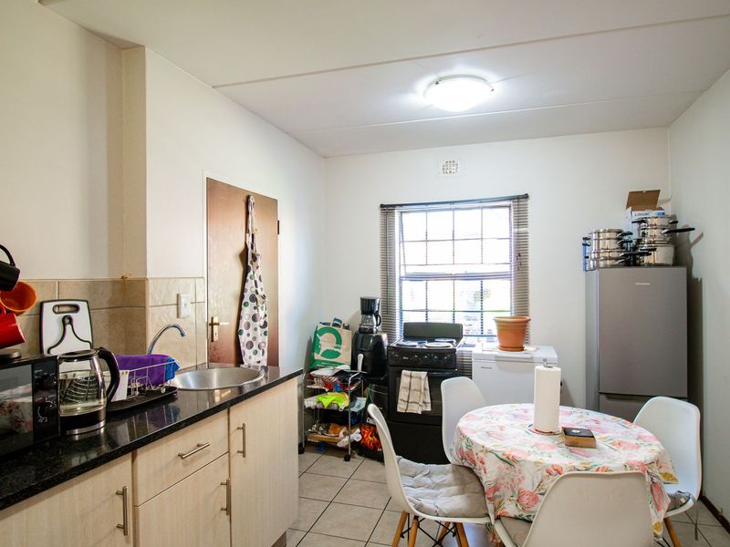 A functional kitchen featuring light-toned cabinetry, granite countertops, a stainless steel sink, and tiled flooring, providing a practical space for meal preparation.