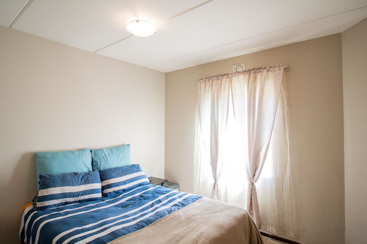 A standard bedroom featuring neutral wall tones, a built-in cupboard, and a window with natural light.