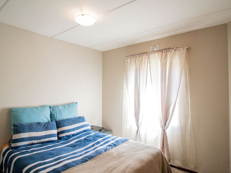 A standard bedroom featuring neutral wall tones, a built-in cupboard, and a window with natural light.