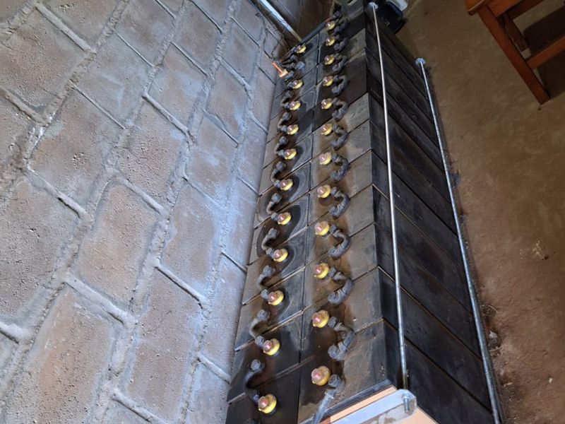 Utility area featuring a solar battery bank and inverter system mounted against exposed brick walls.