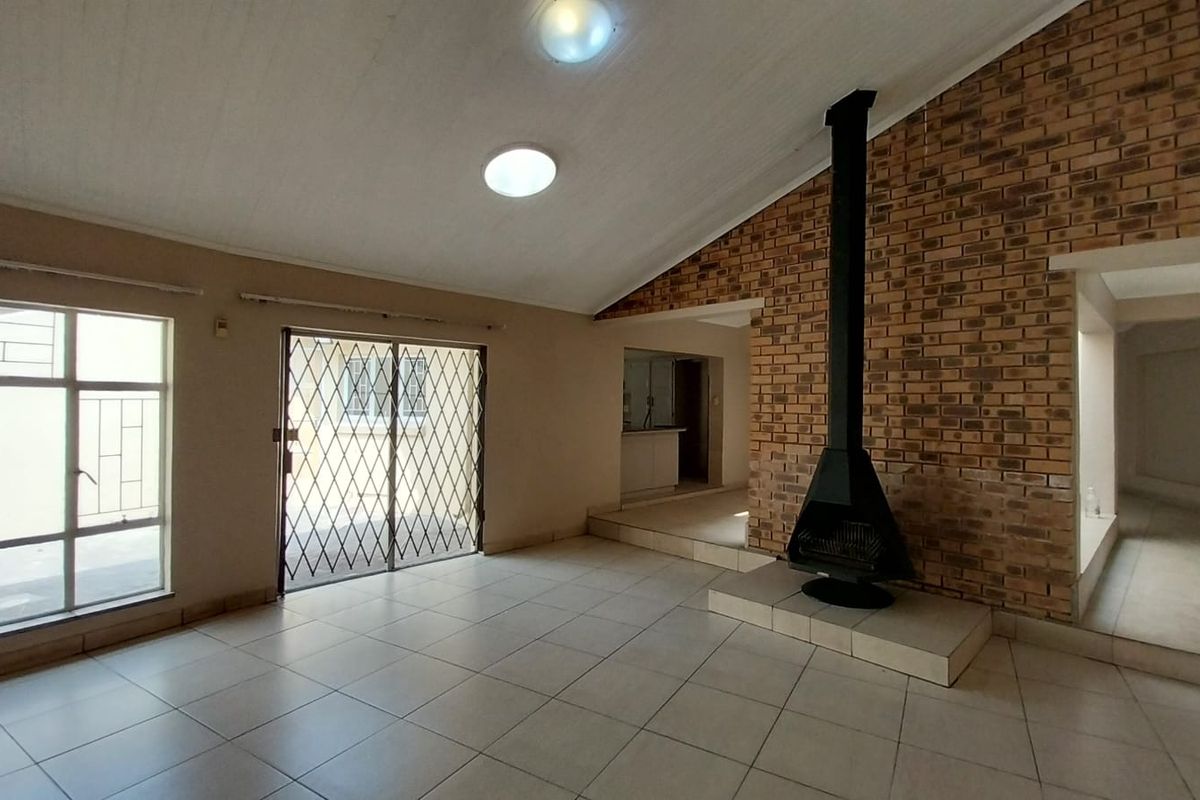 Spacious living area featuring a prominent brick feature wall, a built-in fireplace, tiled flooring, and direct access to the outdoor area.