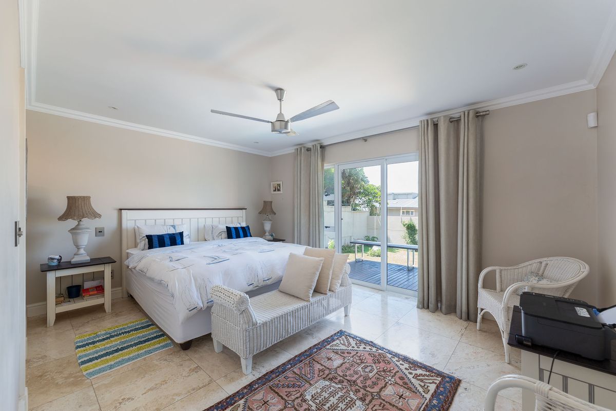 Spacious bedroom featuring neutral tiled flooring, crown molding, a ceiling fan, and sliding glass doors providing direct access to the outdoor patio area.