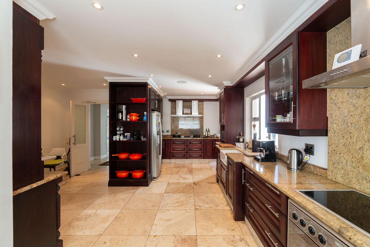 Spacious kitchen featuring dark wood cabinetry, granite countertops, stone flooring, and high-quality built-in appliances with recessed lighting.